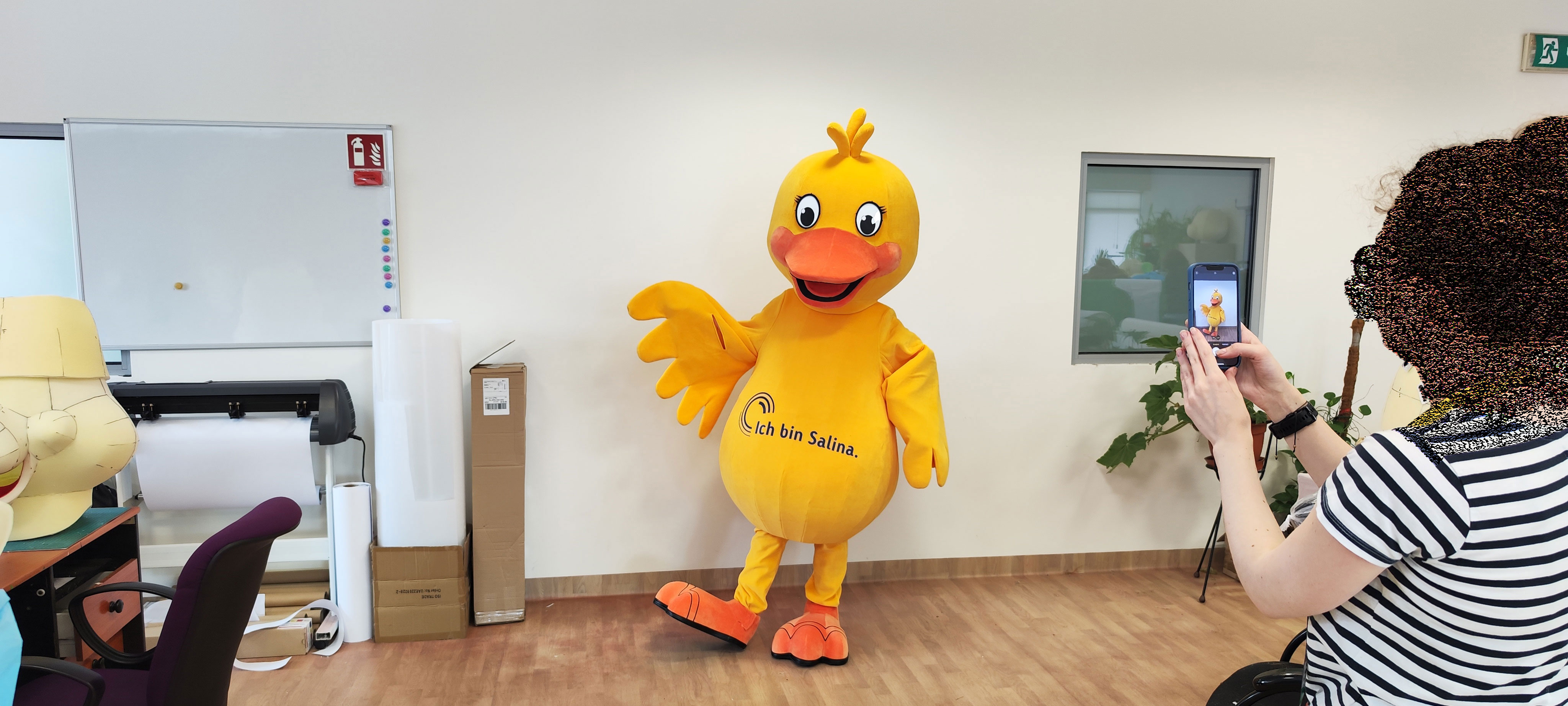 Na fotografii widnieje kostium reklamowy w postaci kaczki pozujący do zdjęcia w siedzibie firmy Elabika